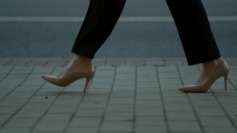 businesswoman is walking in city street, closeup of her feet shod in classic pumps with heels