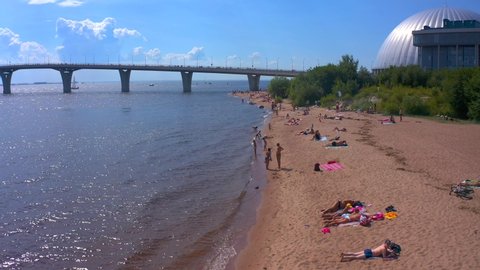 SAINT PETERSBURG, RUSSIA - JULY 18, 2020: Aerial view of the city beach at the Yacht Bridge. Sunbathing adults and children on the beach. Drone flight over the beach on a sunny summer day.