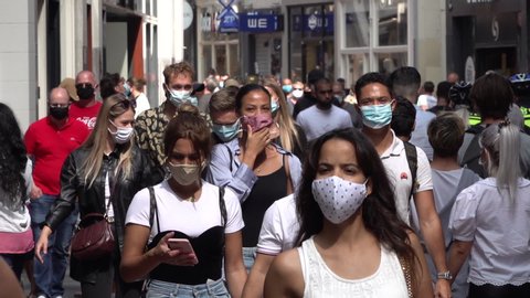 AMSTERDAM, NETHERLANDS – AUGUST 2020: Slow motion of people wearing face masks walking through busy shopping street in Amsterdam, coronavirus Covid-19 pandemic in Europe