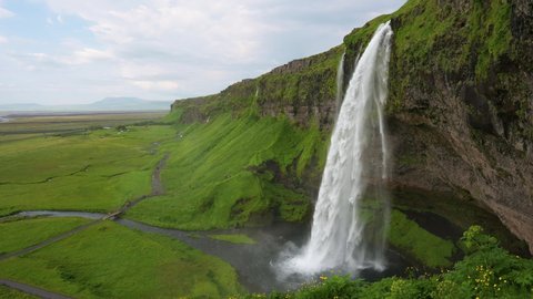 Seljalandsfoss Waterfall located on the Seljalands River in Iceland with seagulls flying around it. 4K UHD video.