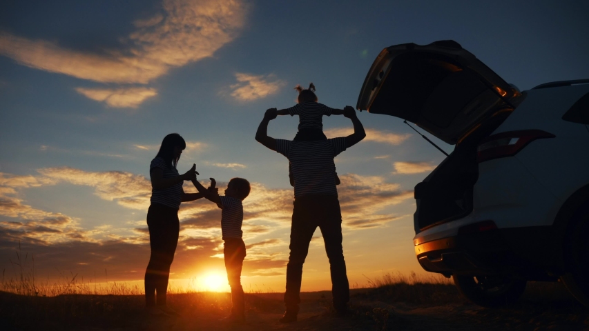 Happy family children kid together standing next to car watching the sunset silhouette in park. family travel dream concept. journey happy family stand with sunlight their backs watching in the park | Shutterstock HD Video #1057821364