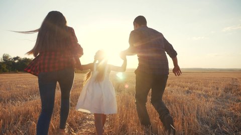 happy family run in the field throw up their daughter. kid dream concept. daughter and parents run across a wheat field near park. happy family dream of happiness. kid child and parents lifestyle run