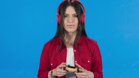 Woman playing video game on a blue background. Slow motion video.