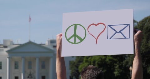 WASHINGTON, DC - Circa Aug, 2020 - A man waves a handmade PEACE LOVE MAIL protest sign outside the White House. The US Postal Service was the focus of attention during the 2020 presidential election.