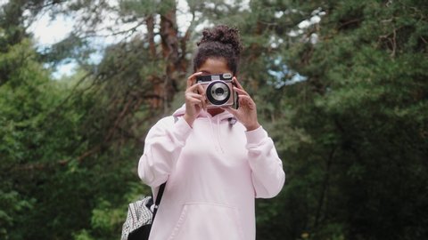 African American woman with analog camera making photo in park, safe travel and explore, walking hiking tours, black tourist girl in wild forest, generation z lifestyle, teenager photographer portrait