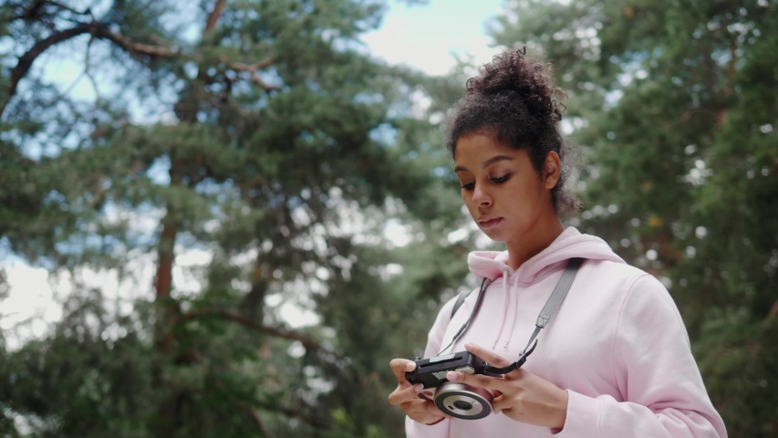 African American woman with analog camera making photo in park, safe travel and explore, walking hiking tours, black tourist girl in wild forest, generation z lifestyle, teenager photographer portrait Royalty-Free Stock Footage #1057827247