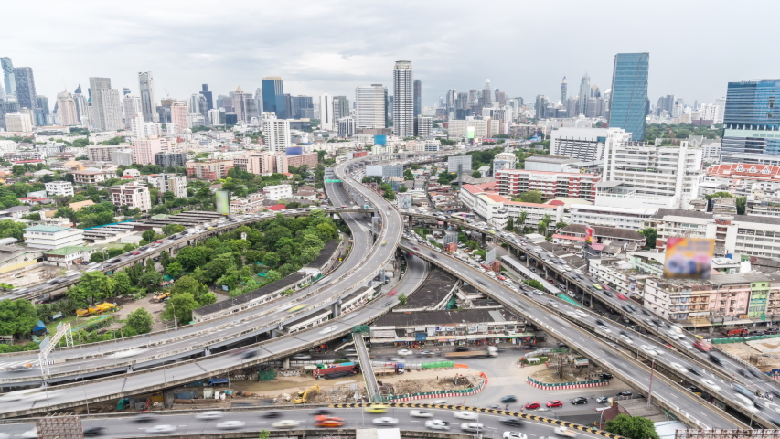 Time-lapse of car traffic transportation on highway road intersection in Bangkok city, Thailand. Public transport, commuter lifestyle, Asian city life concept. Zoom out then still, high angle view Royalty-Free Stock Footage #1057828156