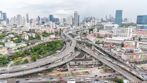 Time-lapse of car traffic transportation on highway road intersection in Bangkok city, Thailand. Public transport, commuter lifestyle, Asian city life concept. Zoom out then still, high angle view
