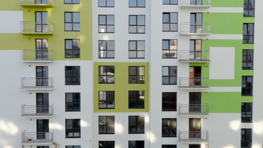 Tilt up view of contemporary apartment building with large windows and colorful walls of the facade of a new house for city residents, or offices with a beautiful modern facade in the early summer - Royalty-Free Stock Footage #1057833184