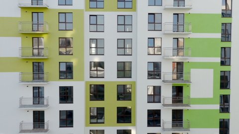 Tilt up view of contemporary apartment building with large windows and colorful walls of the facade of a new house for city residents, or offices with a beautiful modern facade in the early summer -