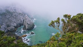 Bizarre rocks at atlantic coastline in morning fog, foliage near Cabo da Roca location, Sintra, Portugal