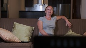 woman laughs watching TV at home. 