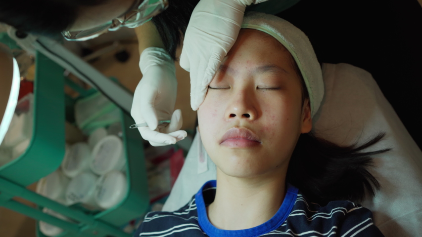 Young Asian female teenager getting her acne and facial treatment | Shutterstock HD Video #1057843390