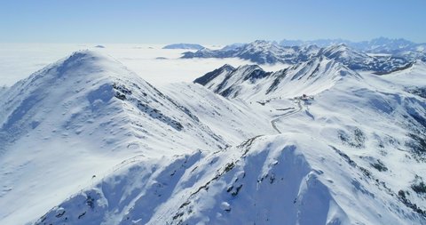 Aerial view of snow mountain range landscape in Sichuan China under blue sky with winding road and sea of clouds in the background 4k winter drone footage