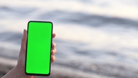 Handheld Camera: back view of brunette holding chroma key green screen smartphone watching content without touching or swiping. Gadgets and contemporary people concept.