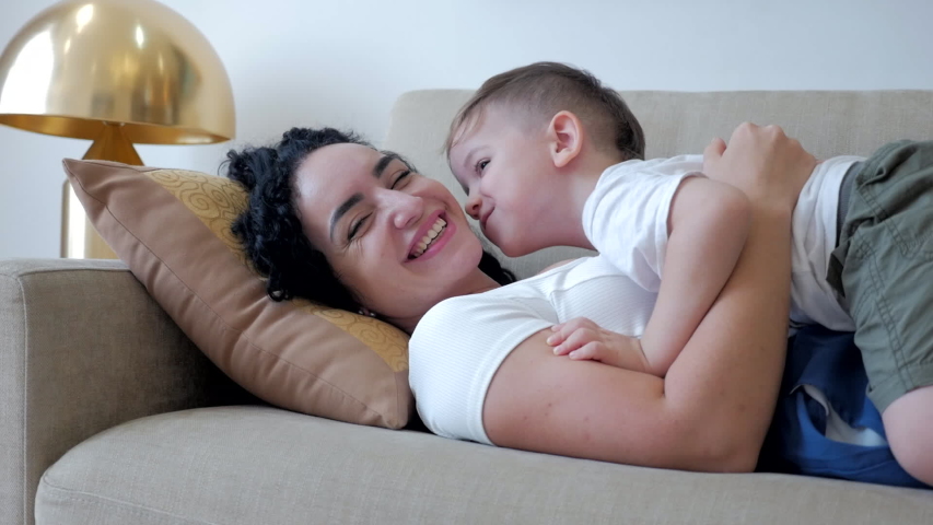 Little son hugs his beloved mother with his hands kisses her on the cheek. 