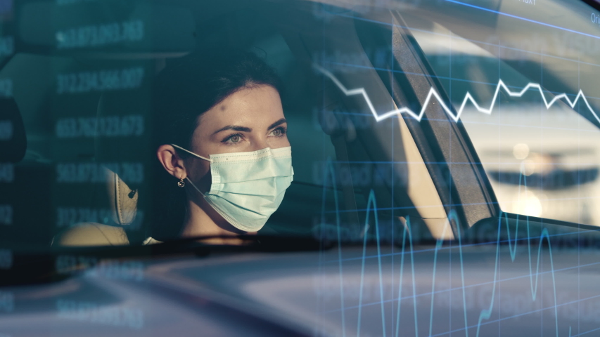 The woman in mask sitting in a car on the hologram background