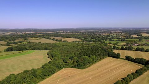 4K aerial drone footage over valley forest and golden crop farm land fields english countryside village summertime, UK