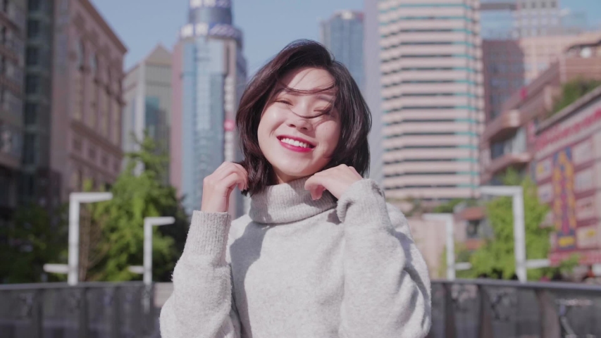 Slow motion of happy Asian girl dancing in the city street shaking head hair flying in the air joyful lovely Chinese young lady in the urban place