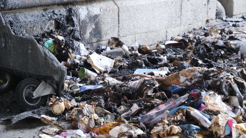 Berlin vandalism burnt out trash can under metro bridge charred debris scattered on sidewalk
