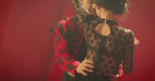 Beautiful couple dancing latin dance . Professional dancers dancing flamenco, rumba or salsa on red background. Pair in spanish dress performs dance movement. Shot ARRI ALEXA Camera