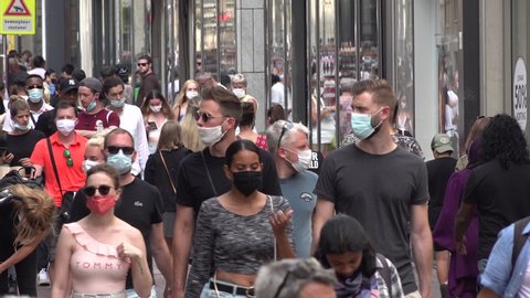 AMSTERDAM, NETHERLANDS – AUGUST 2020: Coronavirus Covid-19 pandemic, crowds of visitors wear compulsory face masks in busy shopping street in Amsterdam, Netherlands Europe