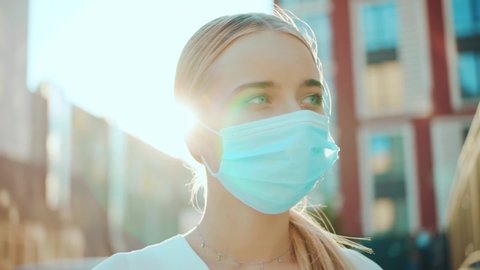 At sunlight young woman wearing protective mask on street look at camera pandemic Covid-19 coronavirus protection quarantine safety prevention flu pollution virus health coronavirus outside