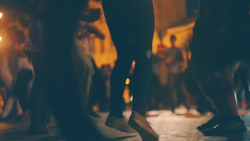 Open-air music festival. Blurred Young people enjoy open-air salsa dancing outside in the street. Blurred Ground level shot of young people dancing salsa on open air event. Many young couples dance Royalty-Free Stock Footage #1057860829