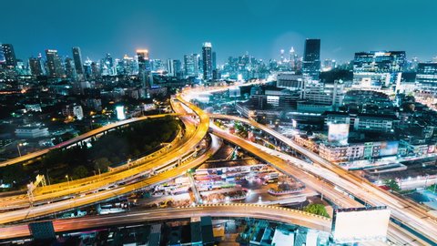 Time-lapse of car traffic transportation on highway road intersection in Bangkok city, Thailand at night under the rain. Public transport, commuter lifestyle, Asian city life concept. High angle view