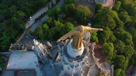 Beautiful opening drone shot over the  Expiatory Church of the Sacred Heart of Jesus (Temple Expiatori del Sagrat Cor) at the sunrise in Tibidabo mountain in Barcelona.
