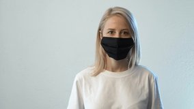 Woman in white t-shirt and black face mask on white background 