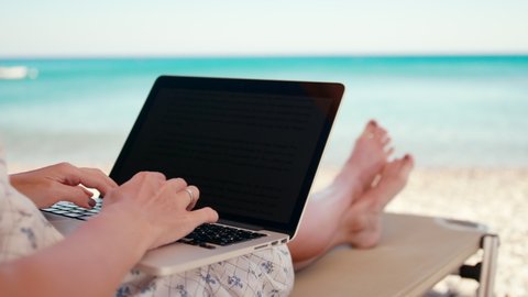 Woman Works Using Laptop on Sea Beach Sunbed in Summer. Unrecognizable Young Lady on Vacation with PC. Female Freelancer or Remote Worker. 4K Handheld Close up Shot