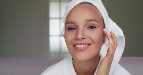 Beautiful Smiling Woman Looking in Mirror, Excited about Perfect Healthy Clear Face Skin. Girl Model in White Bathrobe and Towel Posing for Camera. Natural Beauty Concept.