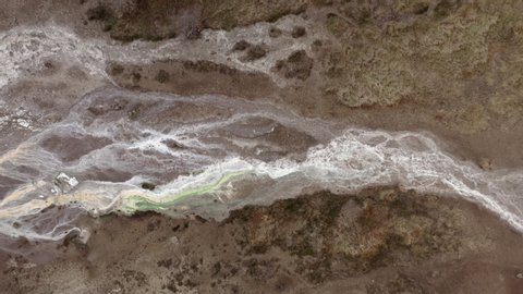 Aerial drone flight over pattern of white salty mineral streaks on the ground from geyser, Iceland, 4k