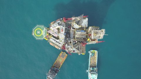 Aerial view from a drone of an offshore jack up rig and offshore supply vessels at the offshore location during day time
