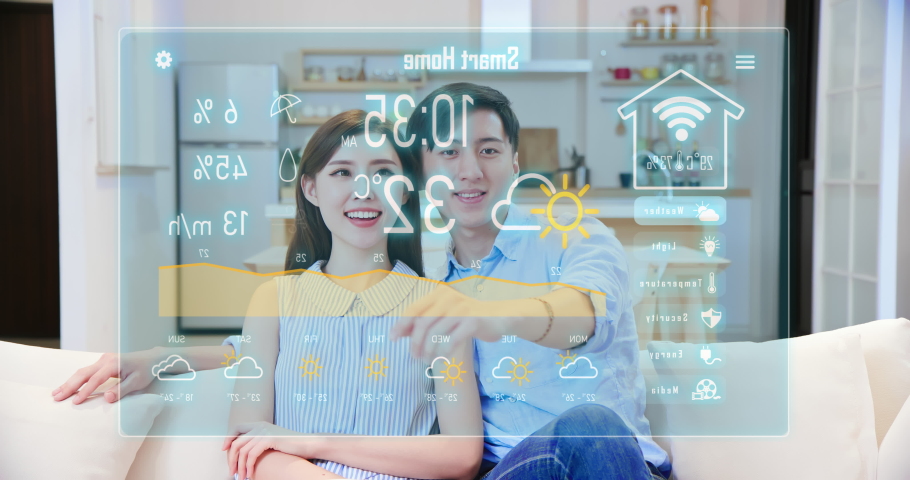 Iot smart home concept - asian couple press virtual screen button and watch housing status on sofa Royalty-Free Stock Footage #1057877959