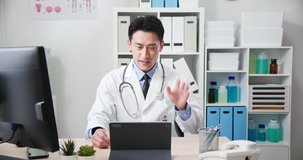 Telemedicine concept - asian male doctor is talking to patient on digital tablet