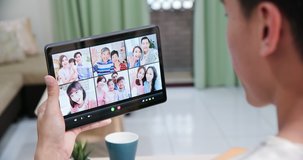 back view of asian man has video chat with family and friends by digital tablet at home happily