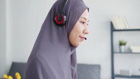 Asia muslim lady wear headphone watch webinar listen online course communicate by conference video call at house. Remotely working from home, social distancing, quarantine for corona virus prevention.