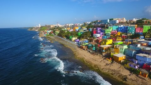 Drone flying above La Perla neighborhood in San Juan Puerto Rico during summer season. Colorful houses close to the beach beautiful paintings sea waves splashing