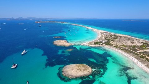 Aerial view of a group of parked yachts at Formentera beach in Spain coast Mediterranean Sea during summer time. Amazing water color blue sky vacation mood tourism boat life beautiful weather sun 