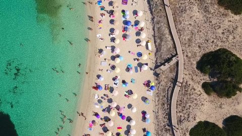 Drone flying above the beach in Formentera island in Spain during summer season. Vacation mode fun tourism people swimming umbrella Mediterranean sea