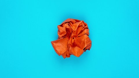 Stop motion animation. Orange paper unfolds from a paper ball and then wrinkles and disappears