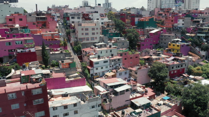 4K aerial over colorful pink low-income favelas in Mexico suburban. Vibrant slum district drone panorama. Poor people living overview. Green latin town in Mexico city. 4K aerial Central America Royalty-Free Stock Footage #1057888087