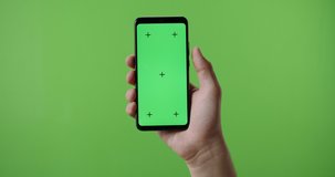 Close up of man's hand holding a smart phone with vertical green mock up chroma key screen and doing gestures on touchscreen 4k template