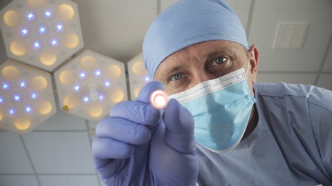 Patient wakes up after a coma. Doctor checks the reaction of the pupils of the eyes with bright light. First-person view, defocus