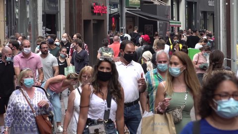 AMSTERDAM, NETHERLANDS - AUGUST 2020: Crowds of people walk through popular shopping street in Amsterdam, they are wearing compulsory face masks due to local Covid-19 corona virus regulation