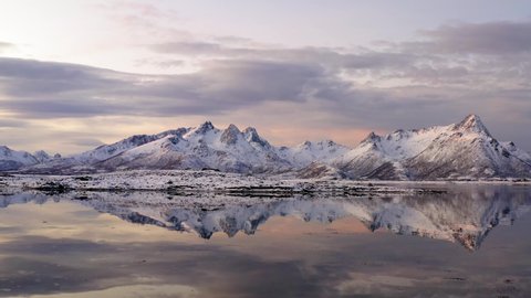 Breathtaking bird's eye view of high mountain rocky peaks covered with white snow reflected in Norway sea water. Breathtaking panoramic fjords landscape of Lofoten in winter, calm beauty of nature 