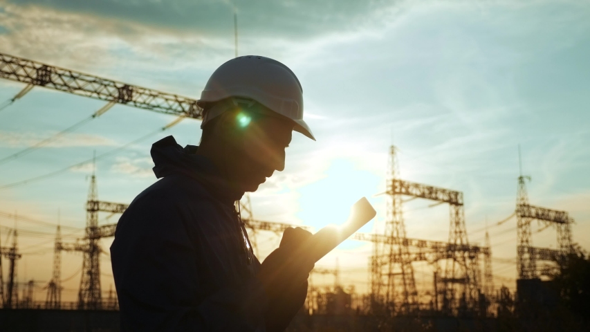 Electrical silhouette worker engineer a working with digital tablet, power near tower with electricity. energy business technology industry concept. electrical engineer studying reading on tablet
 | Shutterstock HD Video #1057893058