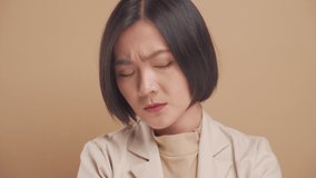 Close up shot of Asian business woman angry and looking at camera isolated over beige background. 4K video